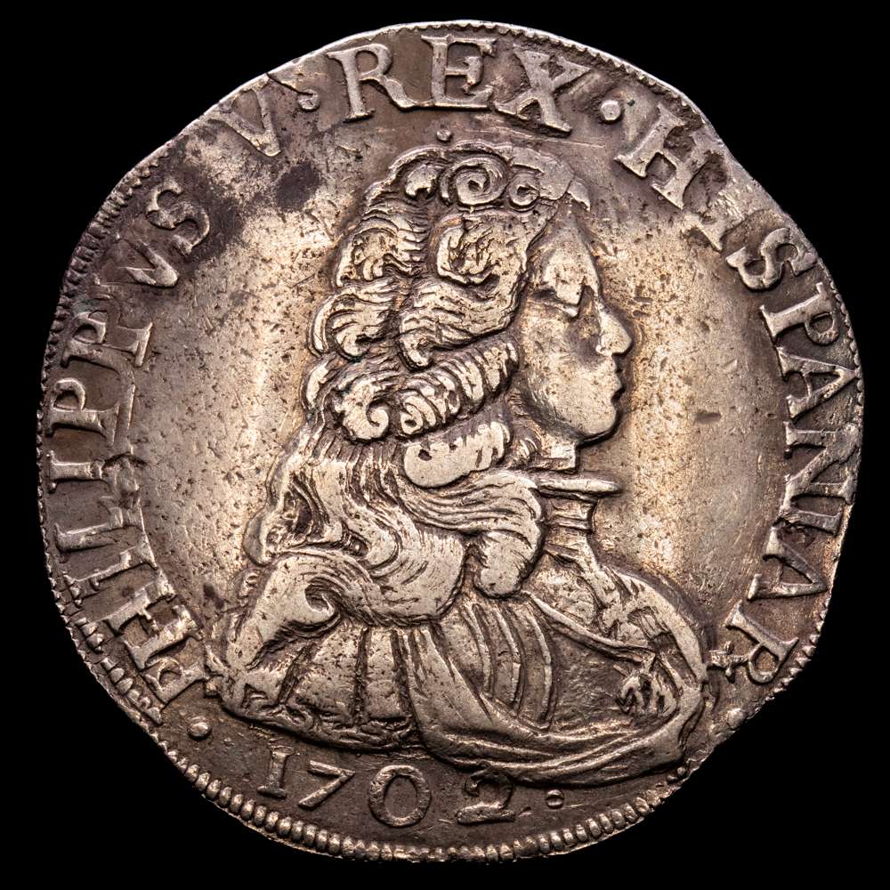 Felipe V. Milán. Escudo. 1702. Olivares 288-R, MIR 393/2; vte. con busto mayor. 27,67 gramos. Magnífico ejemplar, muy centrado. Pátina. Muy escaso así. MBC+.