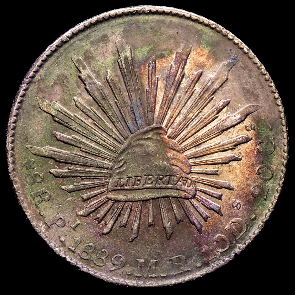 PRIMERA REPÚBLICA KM-377.12 (DP-Pi77) – 8 Reales 1889 San Luis Potosí Pi MR. AU. 26.82g – Patina oscura con tonalidades iridiscentes rodeando los rayos, discreto brillo en ambos lados.